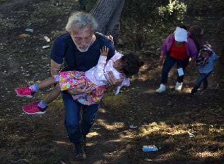 November 25, 2018 - Tijuana, Mexico - Photojournalist carries a little migrant child up a hill after men came and started throwing long sticks at them. They returned to area with Mexican police and believed it to be Americans attacking them. They were met by a line of Mexican police in riot gear at the bridge but managed to run past them, climbing up steep walls, crossing the Rio Tijuana and difficult terrain, reaching the border but were met at times by tear gas from U.S. agents when they tried to climb over fence and were pleading to be let in. Eventually Mexican police moved the crowd, including many women and children back to the shelter. Tijuana Mexico - ZUMAg208 20181125_zap_g208_061 Copyright: xCarolxGuzyx