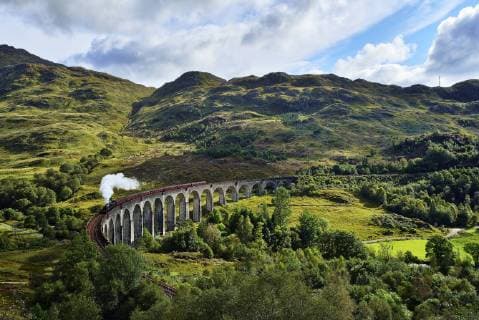 UK, Scotland, Highlands, Glenfinnan viaduct with a steam train passing over it  RUEF01997