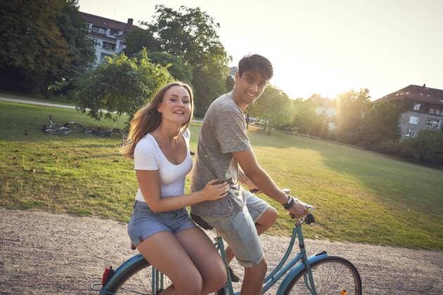 Young couple riding bicycle in park, woman sitting on rack model released Symbolfoto  SRYF00846