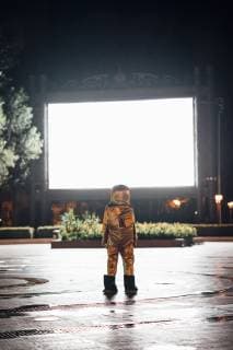 Spaceman on a square at night attracted by shining projection screen model released Symbolfoto  VPIF00754