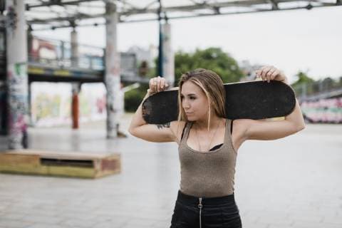 IMAGO Creative: Sommer, Sommertage im Stadtpark Cool young woman carrying skateboard in the city model released Symbolfoto  MAUF01682