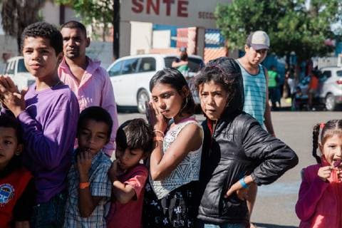 Migrant youths wait for books being distributed by a group of volunteers from Groupo Unitad (United Group) a Christian group table near the Benito Suarez shelter in Tijuana, Mexico. They brought books to help lift the spirits and occupy their time on November 27, 2018.  TIJ20181127098 ARIANAxDREHSLER