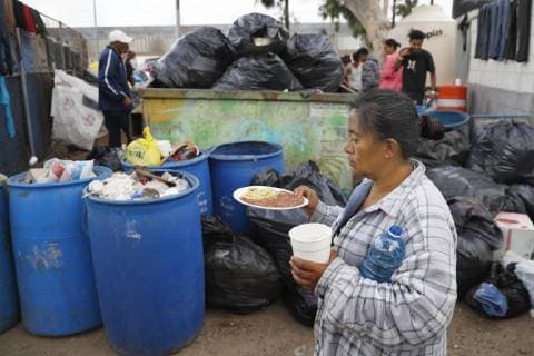 Migrant caravan A migrant from Central America holding food rations walks past a garbage dump in Tijuana, Mexico, on Nov. 28, 2018. 