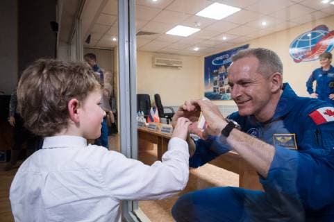News Themen der Woche KW48 News Bilder des Tages Expedition 58 Flight Engineer David Saint-Jacques of the Canadian Space Agency (CSA), right, who is in quarantine, makes a heart with his hands for his son, at the conclusion of a press conference, on December 2, 2018, at the Cosmonaut Hotel in Baikonur, Kazakhstan. Launch of the Soyuz rocket is scheduled for December 3 and will carry Saint-Jacques, Soyuz Commander Oleg Kononenko of Roscosmos, and Flight Engineer Anne McClain of NASA into orbit to begin their six and a half month mission on the International Space Station. NASA  WAX2018120212 AUBREYxGEMIGNANI