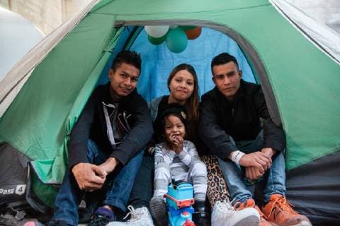 Yeison (left), Johana, their 3 year old son Albert Yared and Yeison s cousin Milson (right) traveled from Honduras with the migrant caravan, they pose for a picture at El Batteral in Tijuana, Mexico on December 9, 2018. All four are staying in a shelter that is specifically for families. To pass the time they go for walks outside the shelter. Johana sometimes purchases a rose and places it in front of the tent.  TJ2018120905 ARIANAxDREHSLER