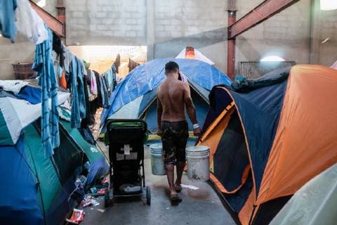 News Bilder des Tages A man carries buckets of water for bathing in El Barretal shelter in Tijuana, Mexico on December 9, 2018. El Barretal is an abandoned concert hall that has the capacity to house 7,500 people but it s not even half full.  TJ2018120911 ARIANAxDREHSLER