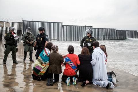 Demonstrators kneel down at Border Field State Park in San Diego, California on December 10, 2018.  SD02018121049 ARIANAxDREHSLER