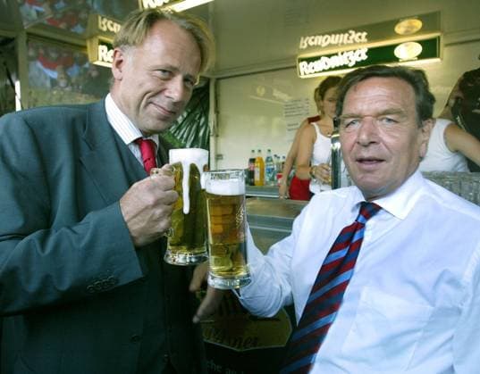 Bundeskanzler Gerhard Schroeder, rechts, und Bundesumweltminister Juergen Trittin, links, trinken Bier waehrend ihres Stadtrundganges durch Grimma am Mittwoch, 13. August 2003. Beide besuchten die saechsische Kreisstadt ein Jahr nach der Hochwasserflut. ( Eckehard Schulz) -----German Chancellor Gerhard Schroeder, right, and the German Enviromental minister Juergen Trittin drink beer during their visit of the town Grimma, eastern Germany, Wednesday, Aug. 13, 2003. Schroeder visited the Saxon town to see, what progress has been made in the rebuilding of the town center which had been devastated during the floods on Tuesday, Aug. 13, 2002. ( Eckehard Schulz) GRIMMA DEU *** Chancellor Gerhard Schroeder right and Environment Minister Juergen Trittin left drinking beer during their city tour through Grimma on Wednes