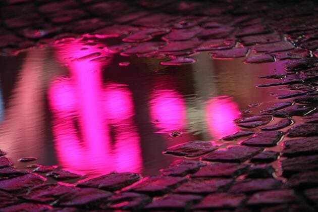Telekom branch reflected in a puddle of rain in downtown Bonn in the evening North Rhine-Westphalia Germany