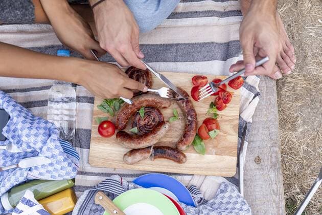 Close-up of couple eating fried sausages and tomatoes outside model released Symbolfoto  FMKF05287