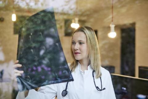 IMAGO Creative: Brustkrebsmonat Female doctor looking at x-ray image behind windowpane model released Symbolfoto  PNEF00982