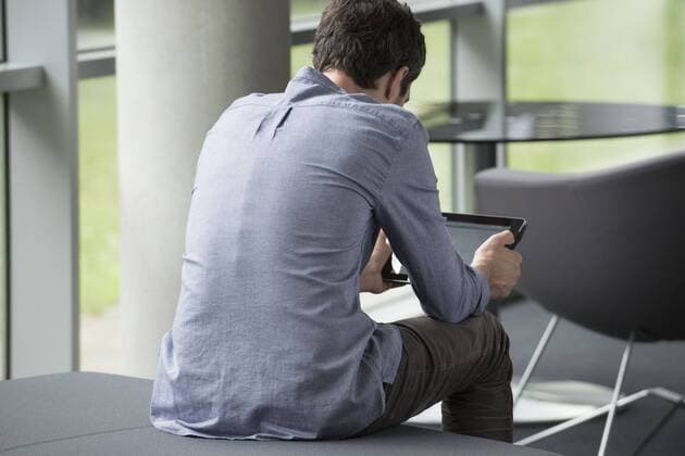 Man sitting alone, looking at digital tablet, rear view  Copyright: EricxAudras B24074524