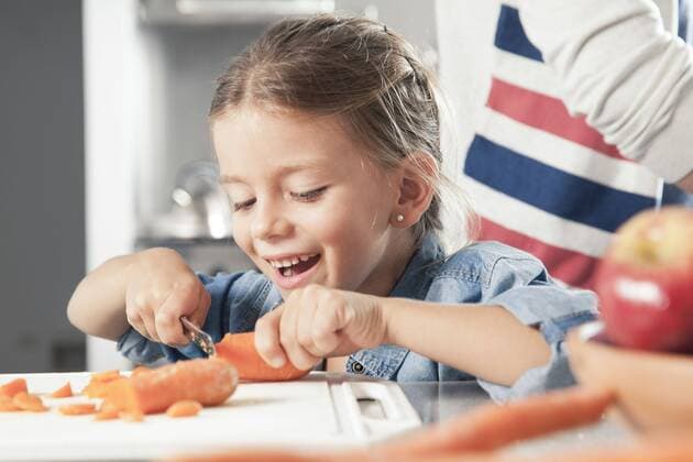Little girl slicing carrots in kitchen  Copyright: SigridxOlsson B32979522