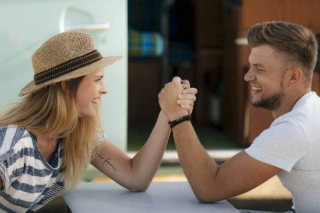 Happy young couple armwrestling at camper van model released Symbolfoto  GUSF01579