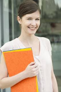 Woman carrying folders, smiling cheerfully, portrait  Copyright: FrédéricxCirou B60773625