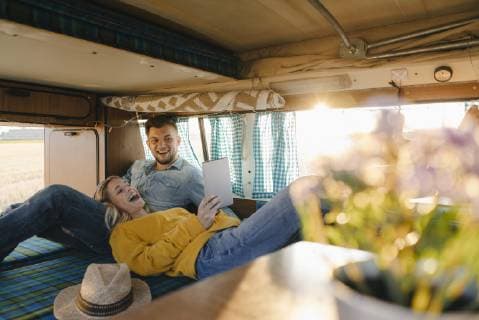 Happy young couple looking at tablet inside camper van model released Symbolfoto  GUSF01409