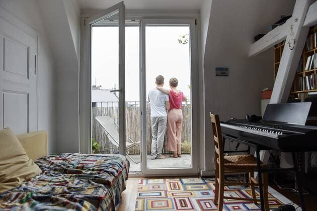 Rear view of couple standing on balcony at home model released Symbolfoto property released  RHF02300