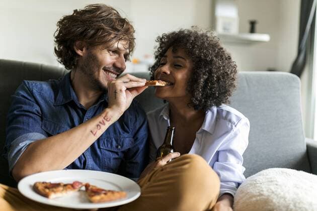 Happy couple sitting on couch eating pizza model released Symbolfoto property released  VABF01817