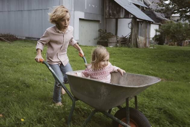 Boy pushing wheelbarrow with his little sister through the garden model released Symbolfoto  KMKF00027