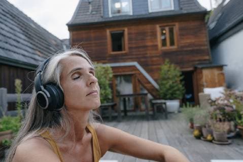 IMAGO Creative: Internationaler Frauenmonat, Gesundheit, Frauen in der Menopause Portrait of mature woman listening music with headphones on terrace model released Symbolfoto property released  KNSF03495
