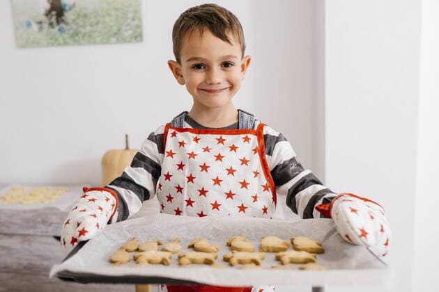 Portrait of smiling little boy holding baking tray with home-made cookies model released Symbolfoto property released  JRFF02357