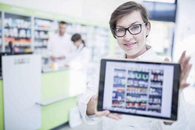 Portrait of smiling pharmacist in pharmacy showing tablet model released Symbolfoto property released  WESTF23993