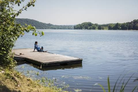 IMAGO Creative: Internationaler Frauenmonat, Gesundheit, Frauen in der Menopause Mature woman sitting on a jetty at a lake, taking a break model released Symbolfoto  MOEF01781
