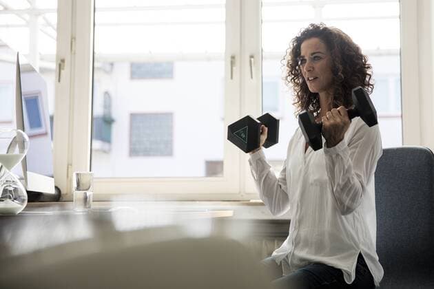 Businesswoman sitting in office, training with dumbbells model released Symbolfoto property released  MOEF01887