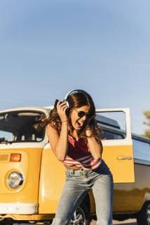 Pretty woman on a road trip with her camper, dancing, listening music model released Symbolfoto  UUF16236