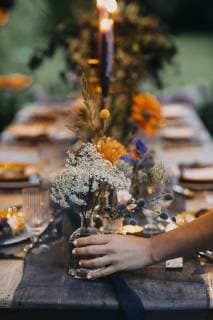 Hand placing flower vase on festive laid table with candles outdoors model released Symbolfoto  ALBF00703