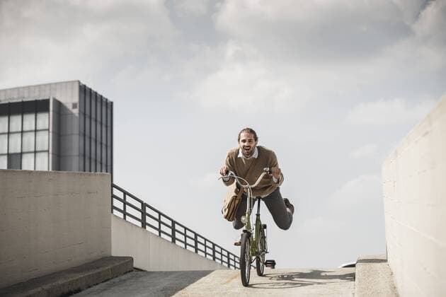 Laughing businessman riding down a ramp on his bicycle model released Symbolfoto  UUF15630