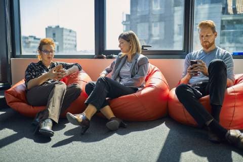 IMAGO Creative: Business - Work-Life Balance Colleagues with cell phones sitting in bean bags in office lounge model released Symbolfoto property released  ZEDF00987