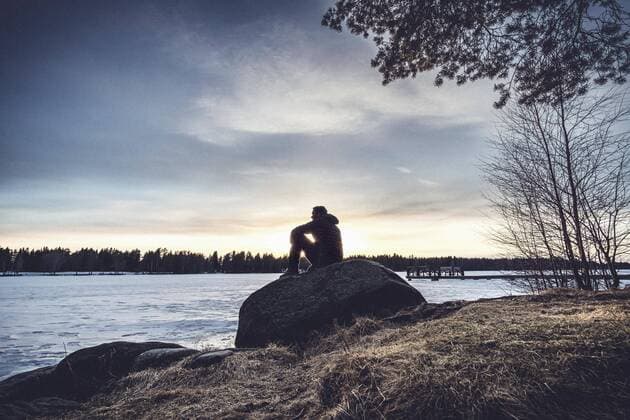 Man sitting on rock overlooking Lake Nydala, Umea, Sweden  Copyright: berkpixels fStopImages1766008
