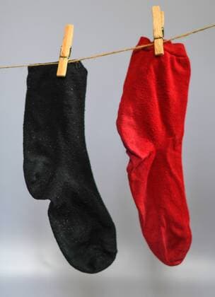 Eine rote und eine schwarze Socke hängen an einer Wäscheleine. Vor zwölf Monaten u ist die schwarz-rote Regierung vereidigt worden. Foto:Winfried Rothermel *** A red and a black sock hanging on a clothesline twelve months ago u the black red government has been sworn in Photo Winfried Rothermel