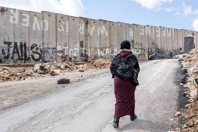 March 27, 2019 - Qalandia, Palestine Territories, Palestine - Palestinian woman walks by separation wall with Ã¢â‚¬ËœImagine War is OverÃ¢â‚¬â ¢ graffiti near Qalandia check point, Palestine on March 27, 2019. Qalandia check point is very busy and important crossing between Palestinian territories in West Bank and Israel. Qalandia Palestine  - ZUMAn230 20190327_zaa_n230_772 Copyright: xDominikaxZarzyckax