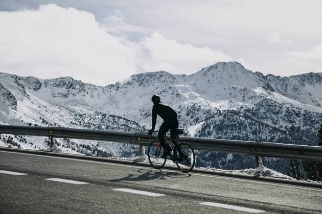 Andorra, cyclist on mountain road with snowy mountains in the background model released Symbolfoto  ACPF00395