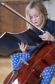 IMAGO Creative: Bildung, Musikerziehung Portrait of blond girl with cello and bow looking at musical notes model released Symbolfoto  HAMF00561