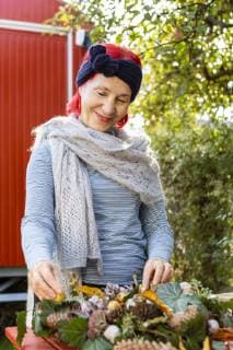 IMAGO Creative: Digitale Welt, Verzicht auf Technologie Portrait of smiling senior woman with red dyed hair tinkering autumnal decoration in the garden model released Symbolfoto property released  OJF00299