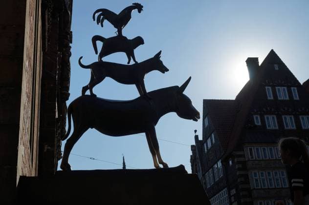The Bremen Town Musicians as Bronze Sculpture by Gerhard Marcks 1889 1981 The monument was erected next to the Bremen Town Hall in 1953 After the world-famous fairy tale from the collection of the Brothers Grimm donkey dog cat and cock expelled a gang of robbers from their house in the woods and thus ultimately never came to Bremen Donkey on the paws or touching the mouth brings luck In the ba
