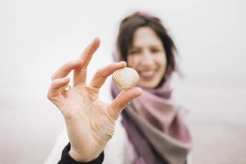 Woman s hand holding collected shell, close-up model released Symbolfoto  KMKF00754