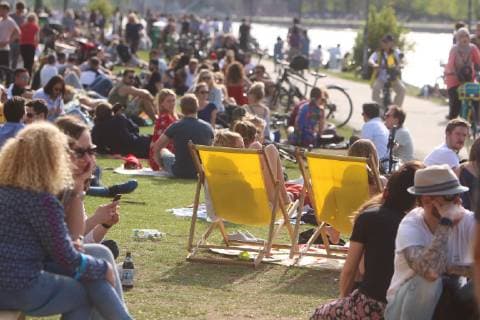 Spring day on Easter Monday in Frankfurt Sun lovers enjoy the warm temperatures and the sunbeams under a blue sky on a sunbathing lawn on the banks of the Main River in the inner city of Hesse Germany