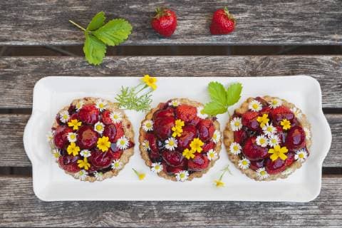 Homemade strawberry heart tartlets with daisy flowers and golden marigold, edible flowers, dark wood  GWF06024