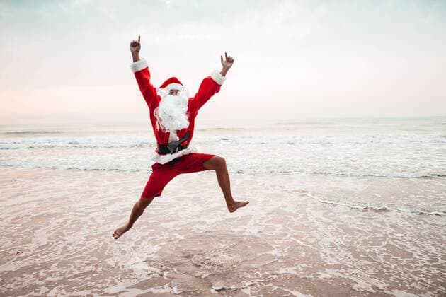 Thailand, man dressed up as Santa Claus jumping in the air at seashore model released Symbolfoto  HMEF00217