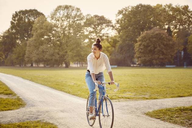 Young woman riding bike at a park model released Symbolfoto  JHAF00048