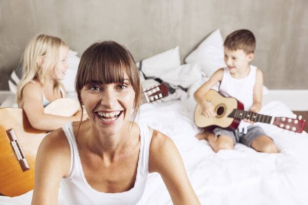 happy mother with children playing guitar in bed model released Symbolfoto property released  MCF00054