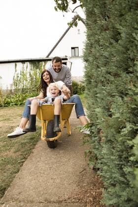 Playful man pushing wife and son sitting in wheelbarrow in garden model released Symbolfoto property released  MFRF01278