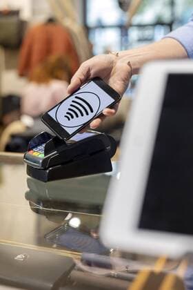 Customer paying contactless with smartphone in a fashion store model released Symbolfoto property released  PESF01532