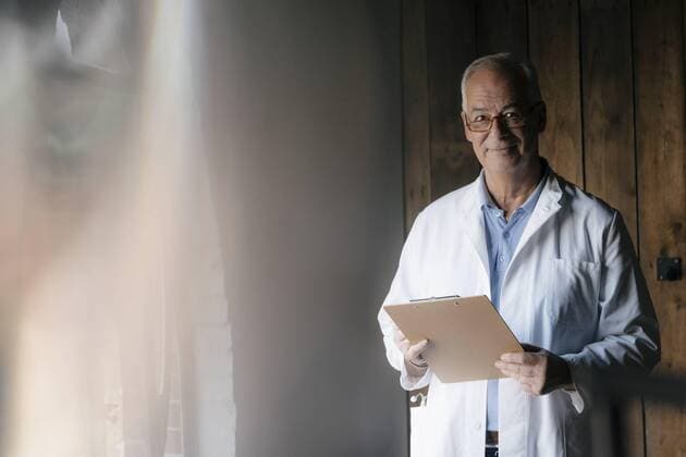 Smiling senior doctor holding clipboard model released Symbolfoto property released  JOSF02927