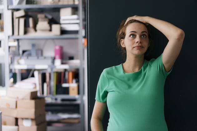 Pregnant woman standing a wall in office looking up model released Symbolfoto property released  KNSF05430