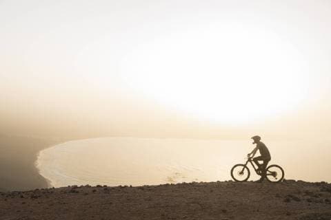 Spain, Lanzarote, mountainbiker on a trip at the coast at sunset model released Symbolfoto  AHSF00109